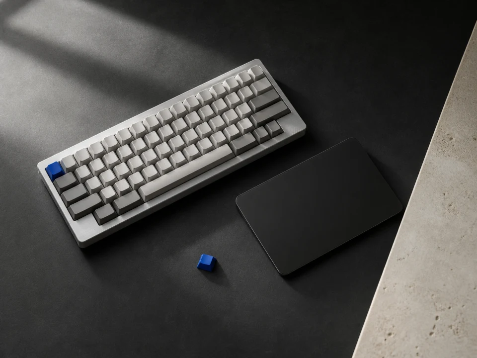 A silver keyboard and black trackpad on a dark desk